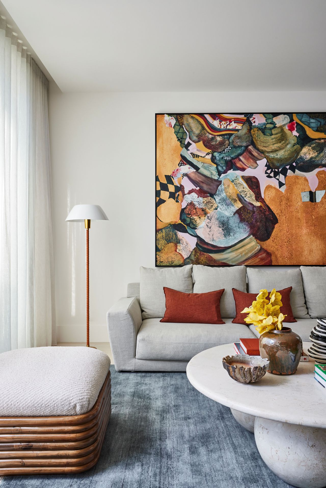 Living room featuring a light blue velvet cursh rug anf burnt red pillow accents atop of a cream colored couch, inspired by the color palette of Wes Anderson's "The Phoenician Scheme"