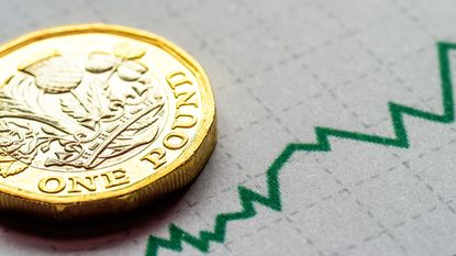 UK pound coin next to a financial growth chart