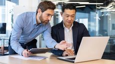 Two businessmen looking at a laptop computer together.