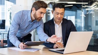 Two businessmen looking at a laptop computer together.