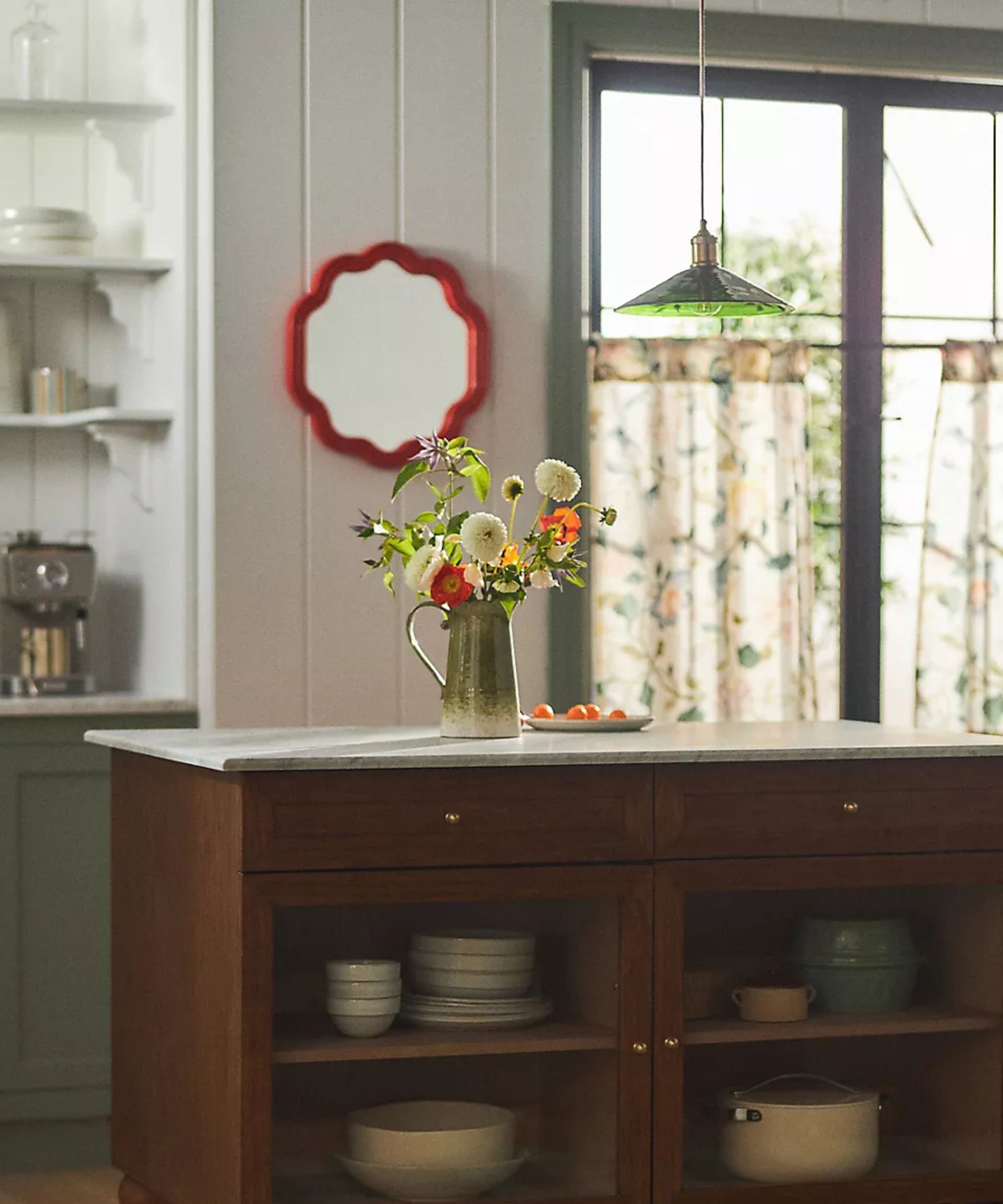 A kitchen with a wooden island and a green glass pendant light