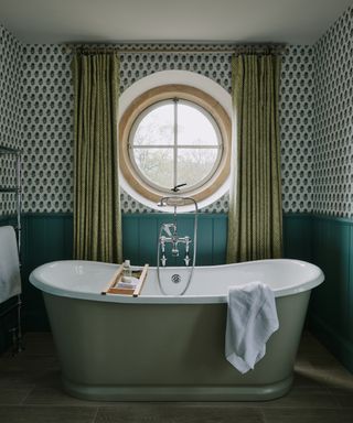 drapes vs blinds, green bathroom with round window, green drapes, green wallpaper, teal shiplap/wainscotting, green painted roll top bath