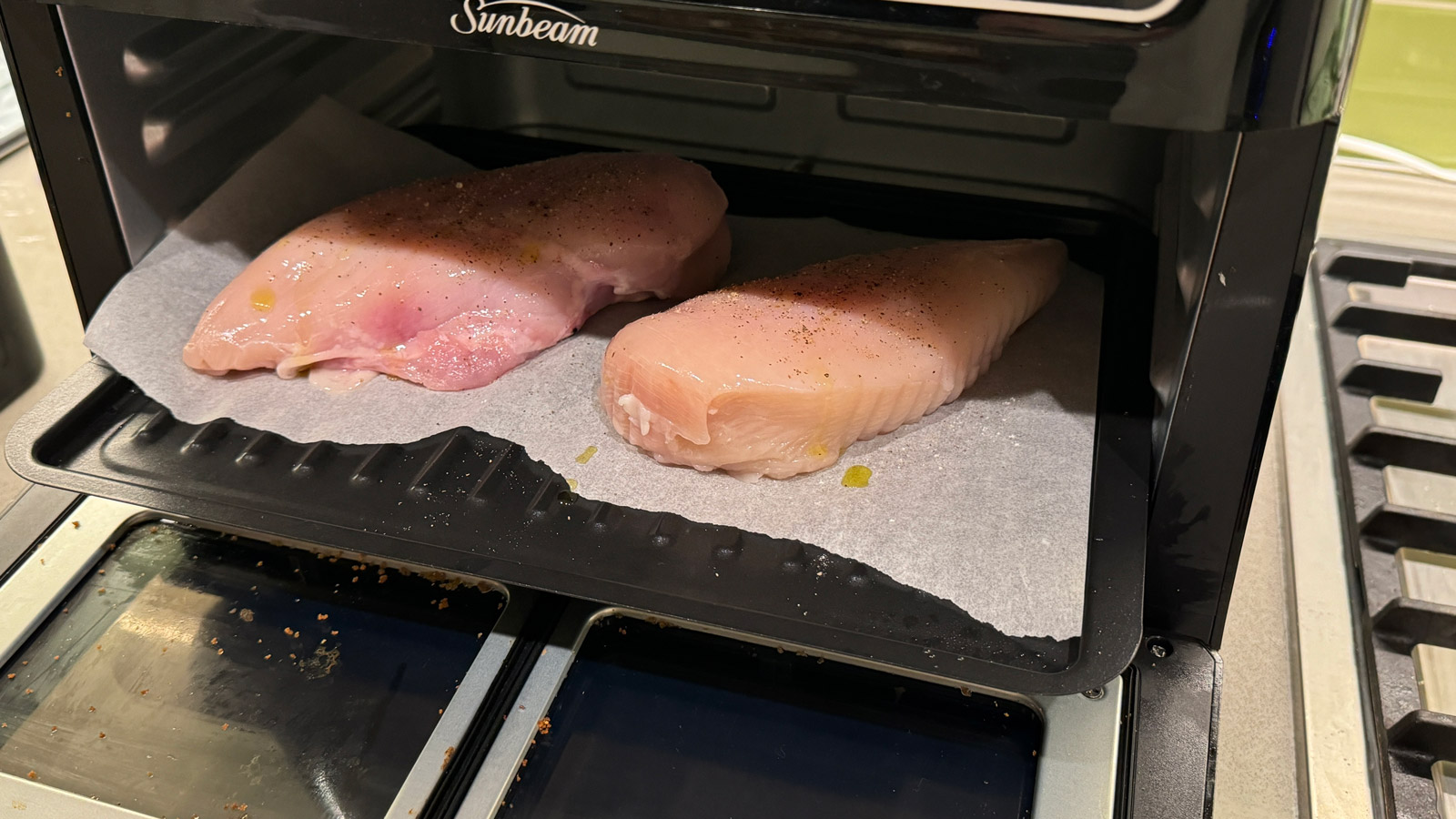 Two uncooked chicken breasts on a roasting tray in the Sunbeam Multi Zone Air Fryer Oven