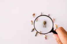 A magnifying glass examining a small toy model of a human