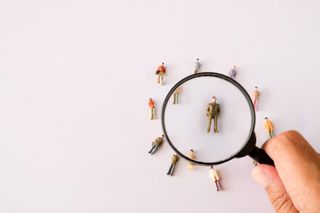 A magnifying glass examining a small toy model of a human