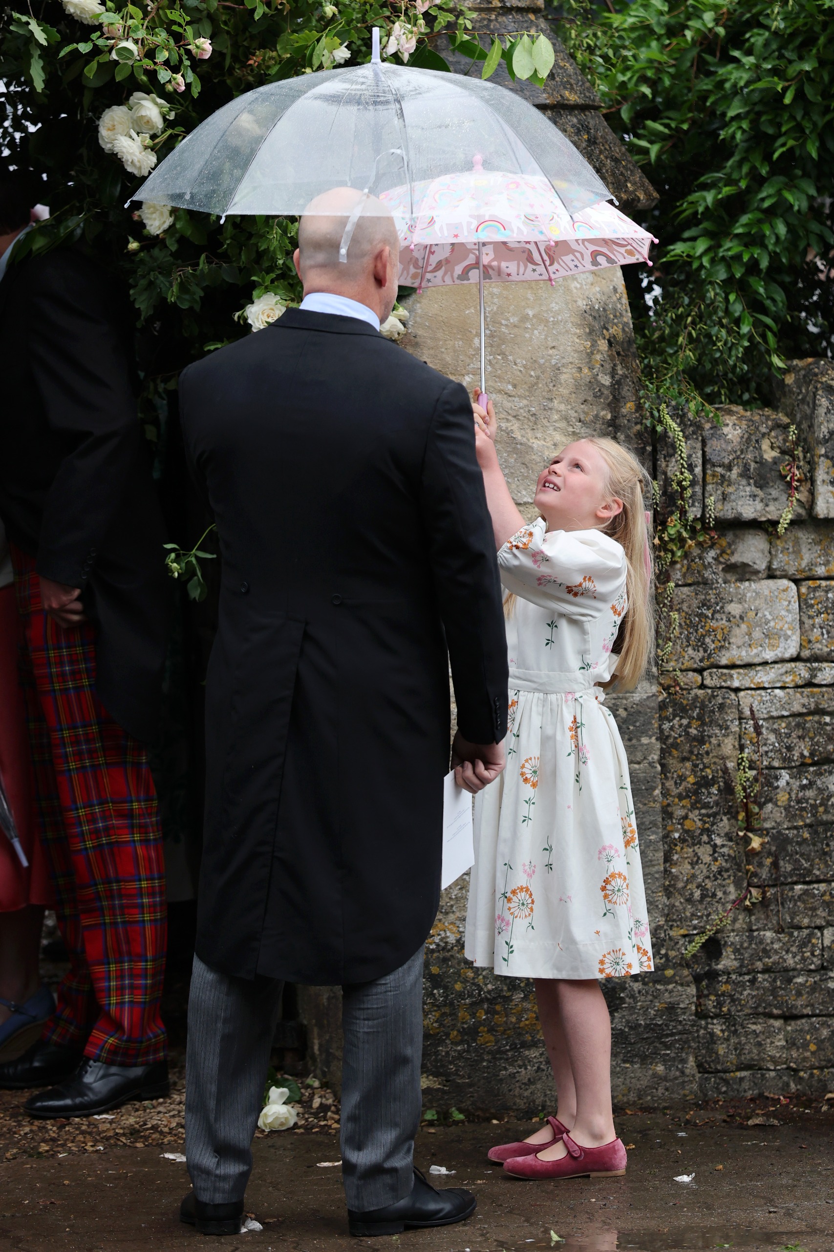 Lena Tindall in a white dress holding an umbrella next to dad Mike Tindall
