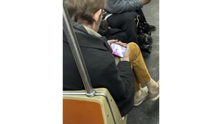 Ein durchgesickertes Foto eines Google Pixel Fold: Jemand sitzt im Zug und nutzt einen durchsichtigen Dummy