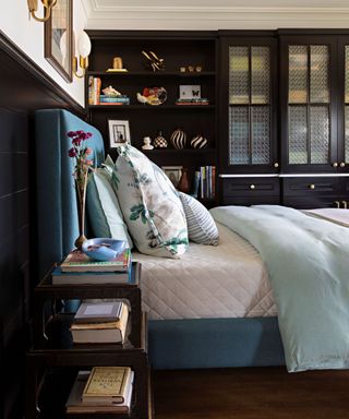 A blue bed with a white mattress in a bedroom with dark brown shelving units and nightstand with teal bedframe and headboard