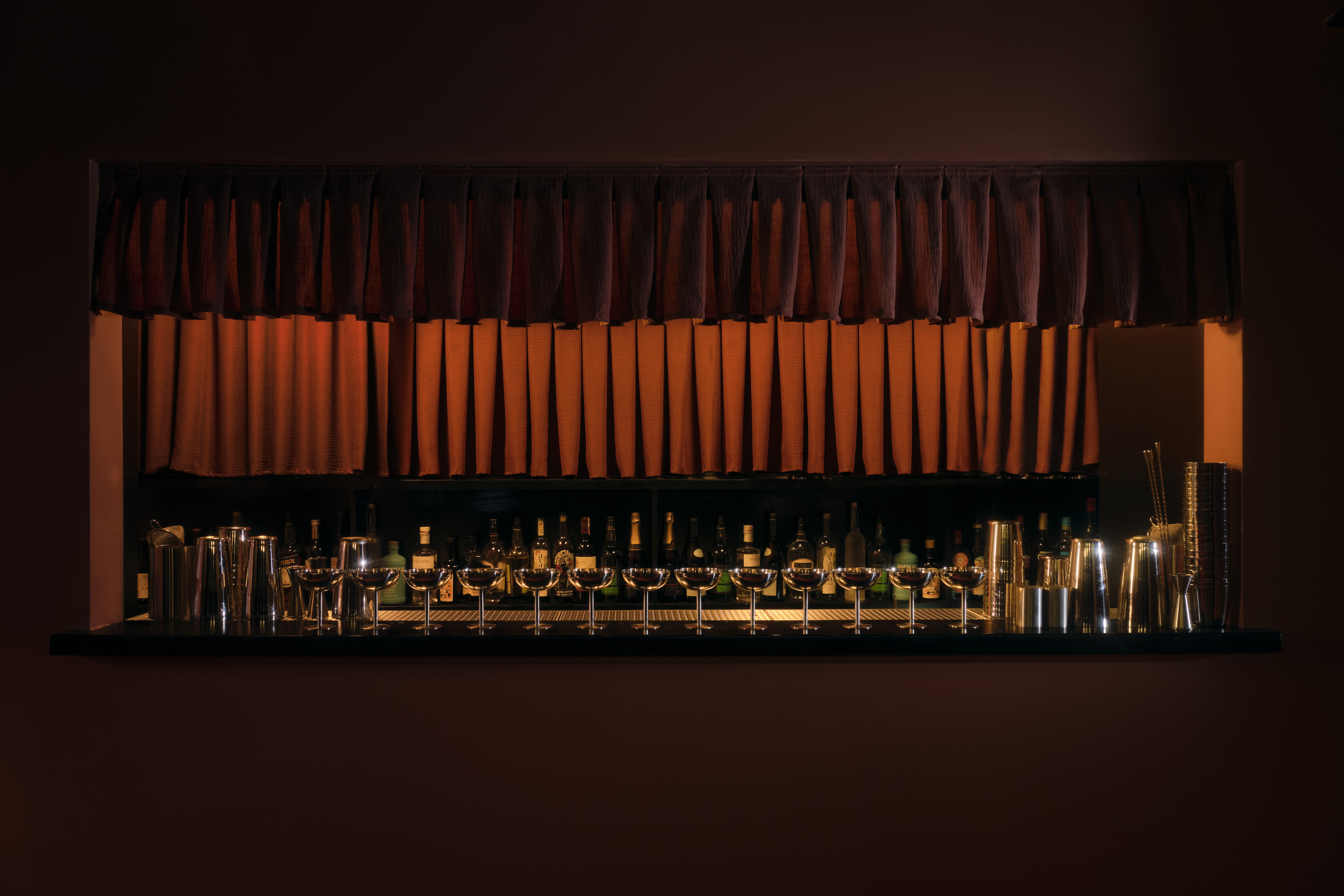 A golden-hued, dimly lit nightclub features velvety red or ochre plush fabrics, reflective surfaces, Art Deco-inspired sconces, and an air of mystery.