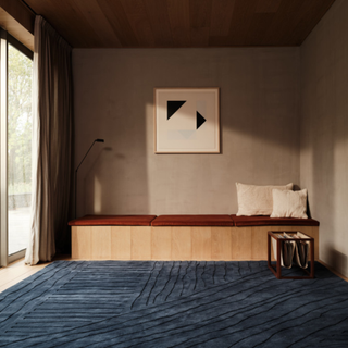 blue textured rug in a room with a wooden bench, pillows, and magazine holder