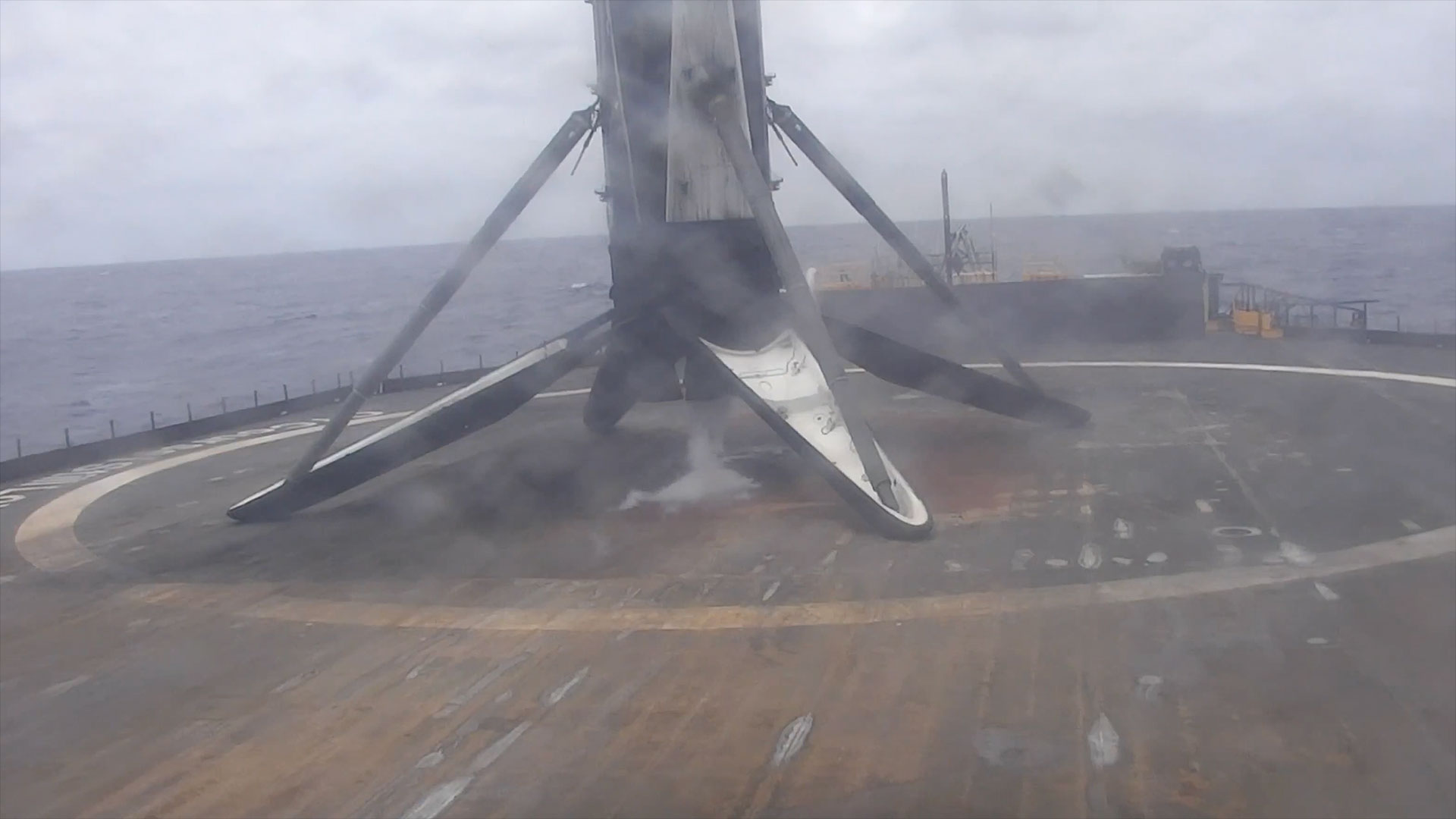 the first stage of a rocket is seen standing vertically on its four legs after touching down from space on an ocean-based platform