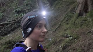 A woman wearing a headlamp on the trail