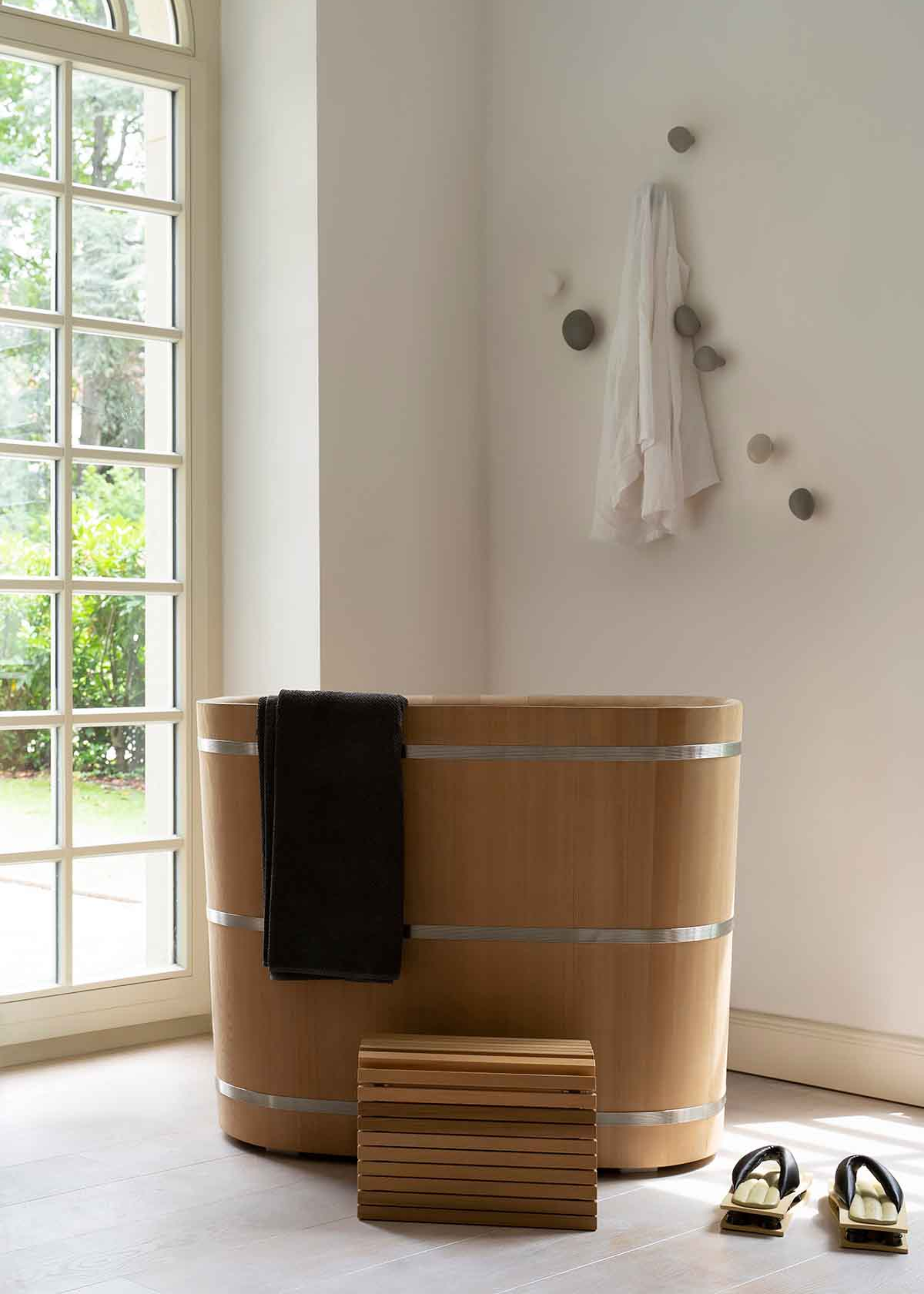 A wooden traditional Japanese ofuro with a wooden step-stool, and a pair of traditional slippers