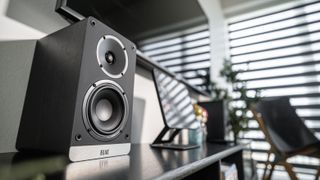 elac debut connex speakers on stand with TV in background