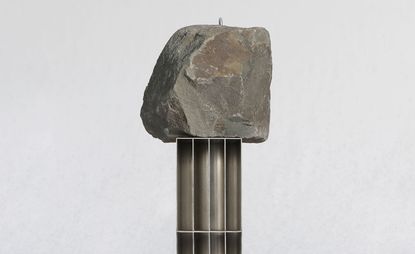 Sculptural piece by Jinsik Kim featuring a metal base and large rock on top