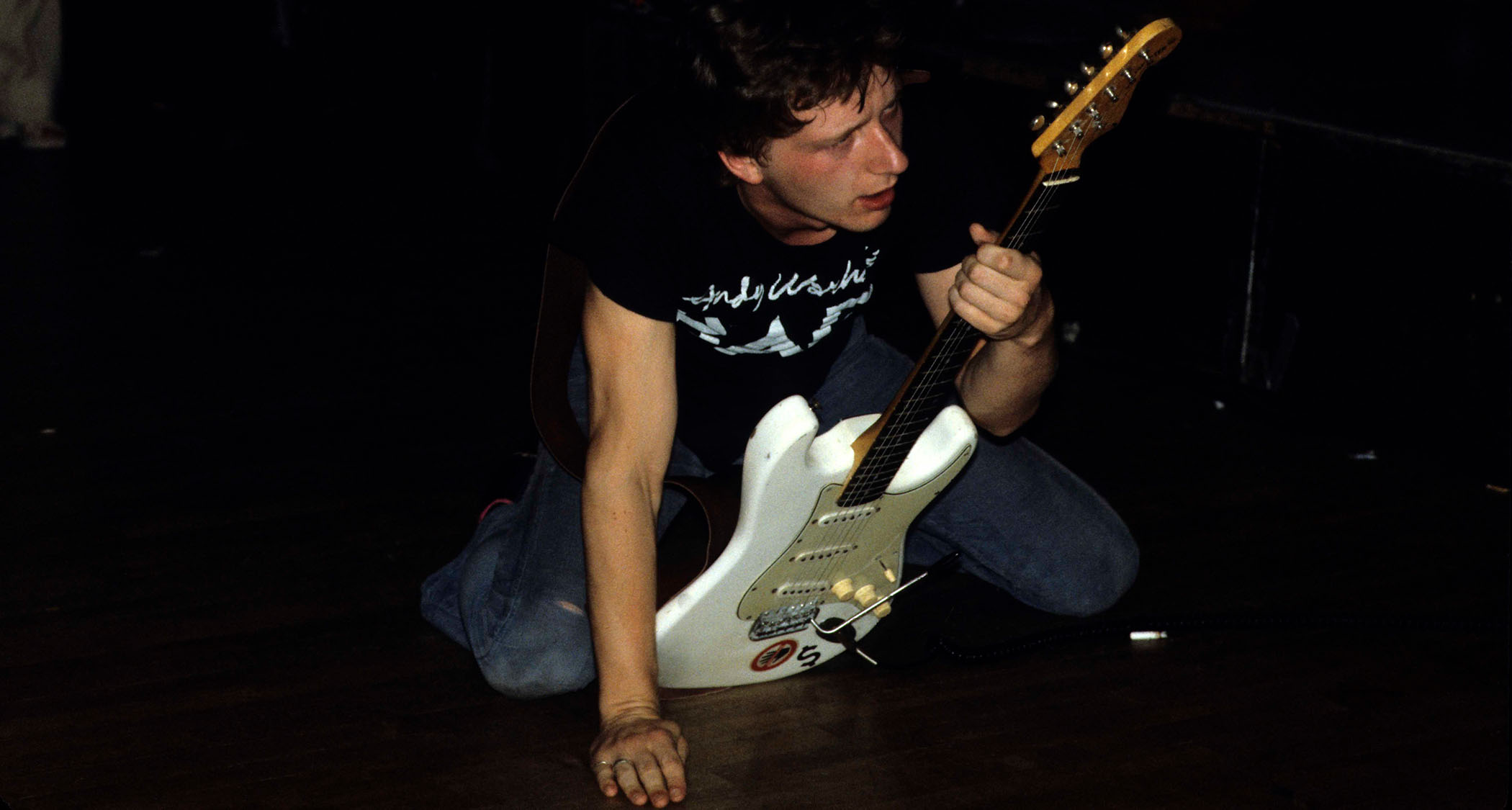 Glenn Tilbrook of Squeeze on his knees, onstage with his white Stratocaster:  Tilbrook knows a thing or two about using inventive and interesting chord voicings in the band’s songs