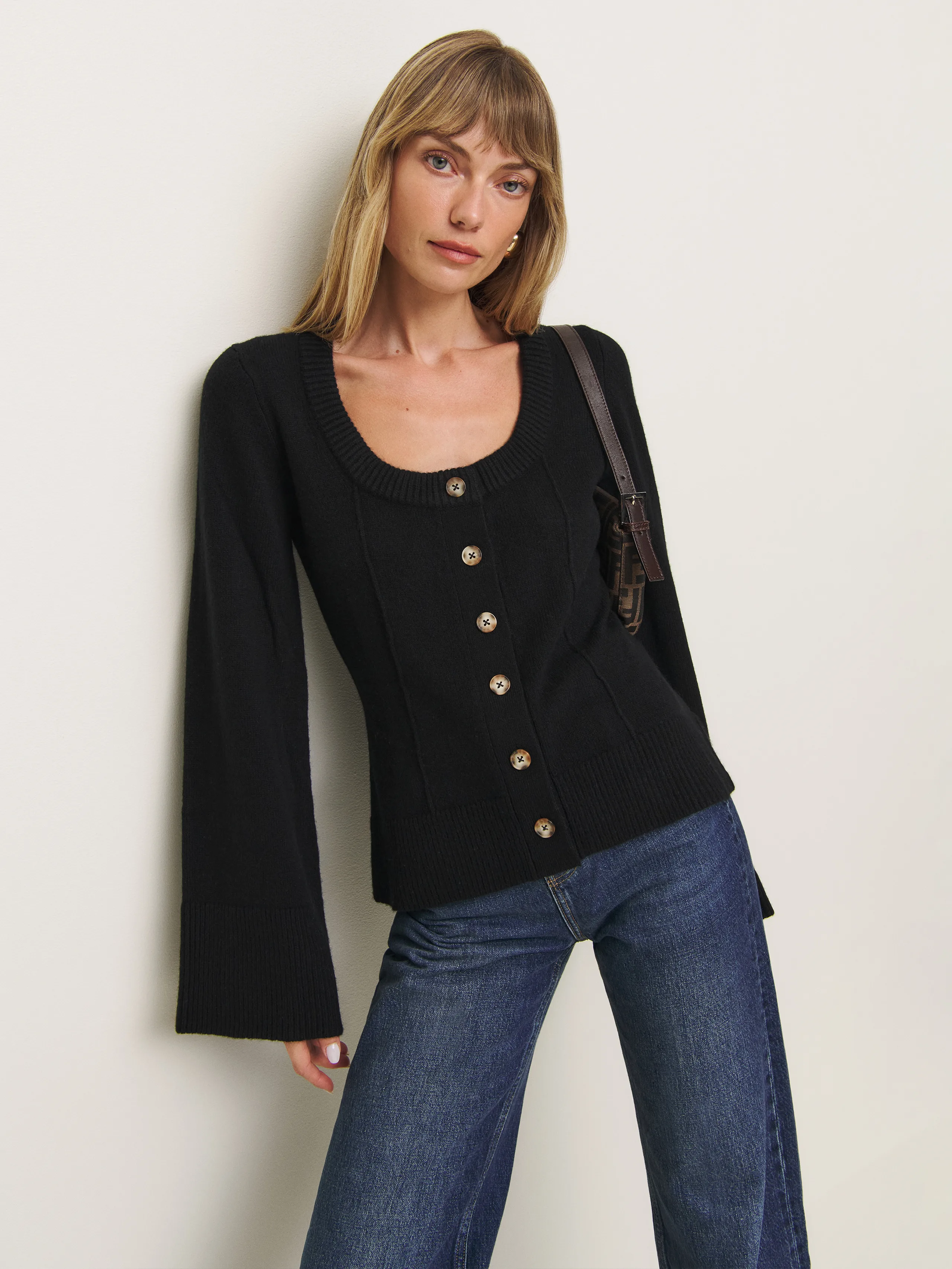 Woman wears black scoop neck cardigan and blue jeans