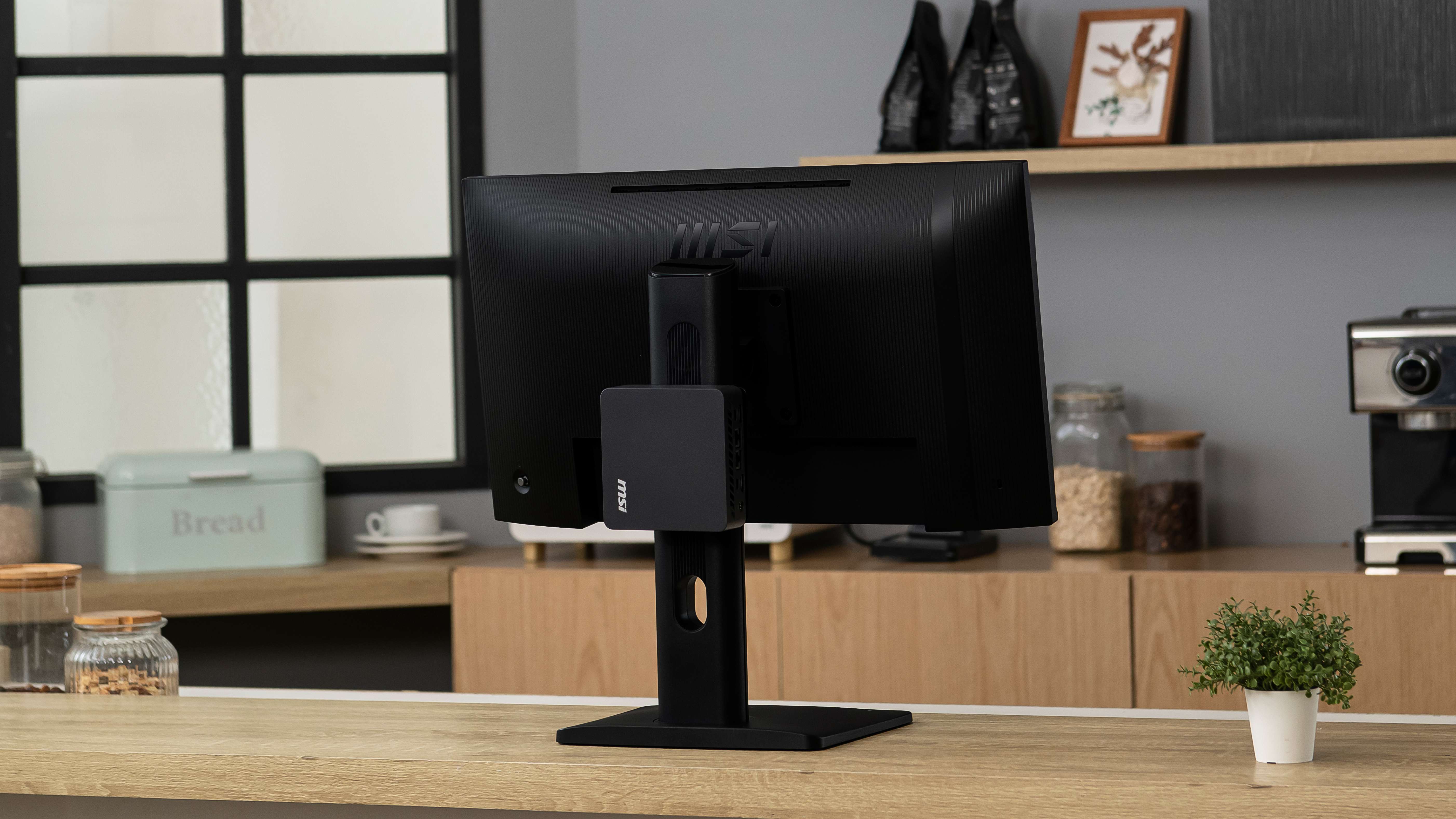 The MSI Cubi NUC AI+ 3MG attached to the back of a monitor.