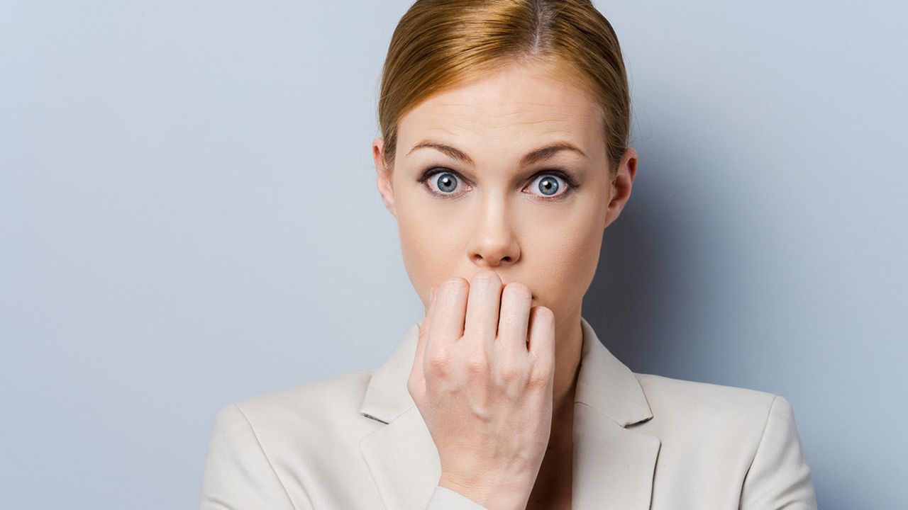 A businesswoman bites her nails.