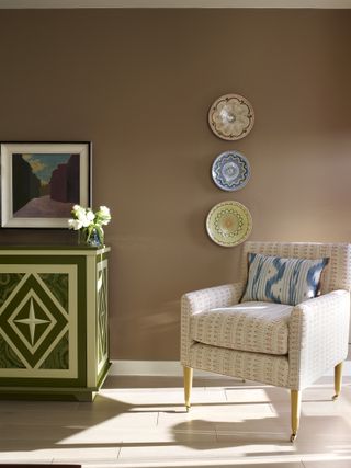 A floral arm chair with a light brown wall backdrop