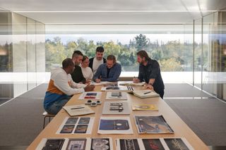 View of Apple Design Team members at a meeting table in Apple Park with iPhone prototypes
