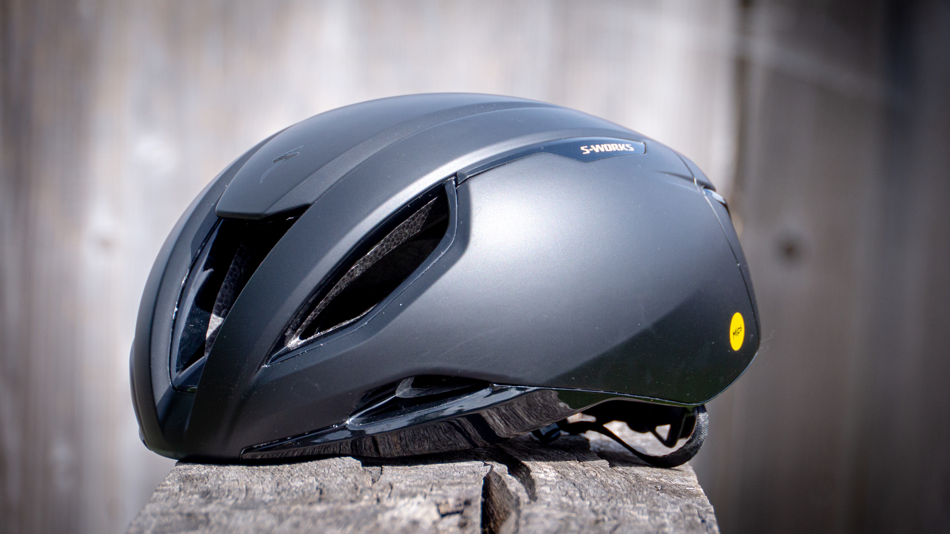 An front-angle view of a black S-works Evade 3 helmet sitting on a wooden bench
