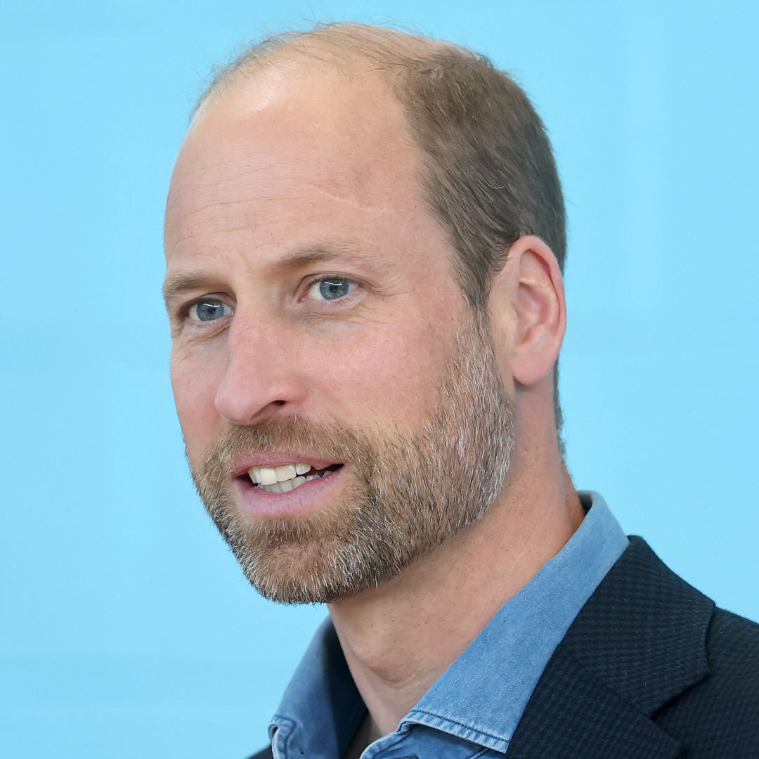 A headshot of Prince William smiling in a blue shirt