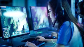 Girl sat in front of gaming monitor with headset on playing League of Legends