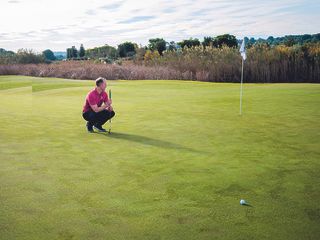 Golf Monthly Top 50 Coach John Howells reading a putt on the green