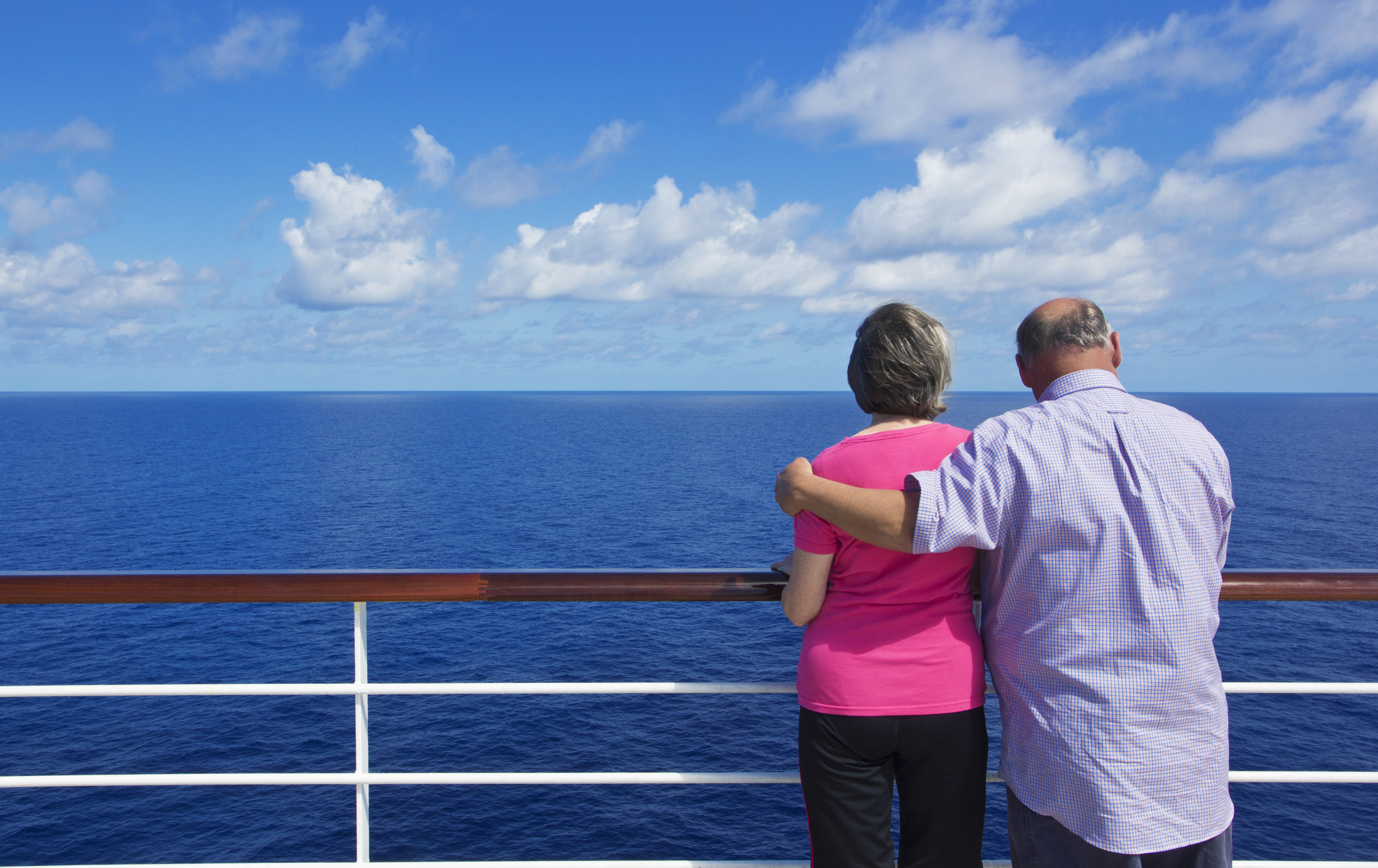 A senior couple looking out at the ocean while on deck a cruise ship