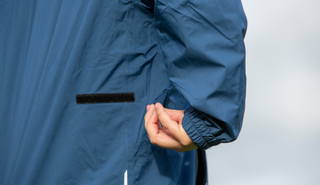 A golfer adjusts the side of the ProQuip StormForce PX8 Rain Jacket