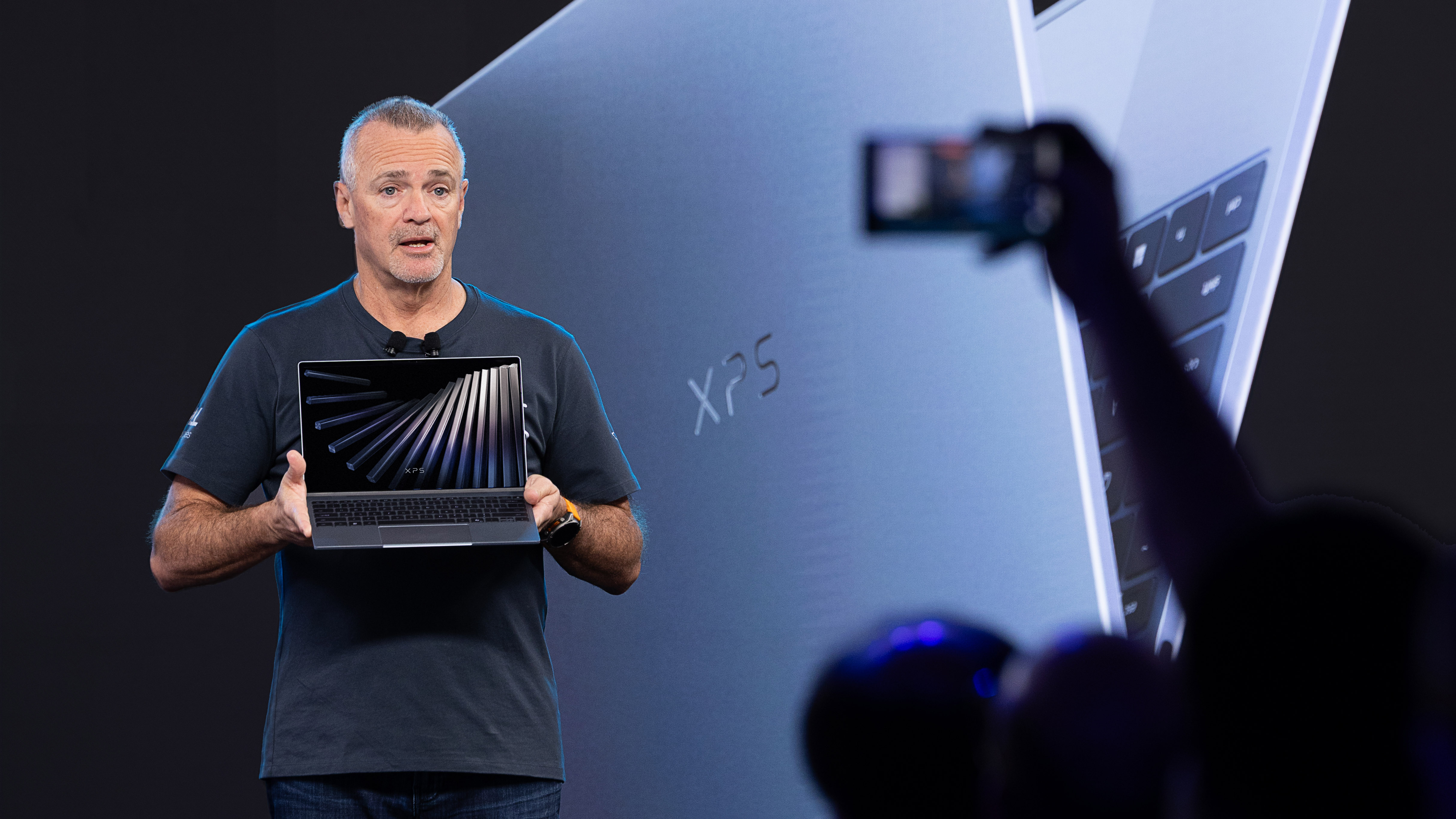 A man in a black shirt holding a Dell XPS laptop on a stage at CES 2026