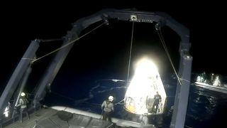 a white cone-shaped capsule is lifted onto a boat