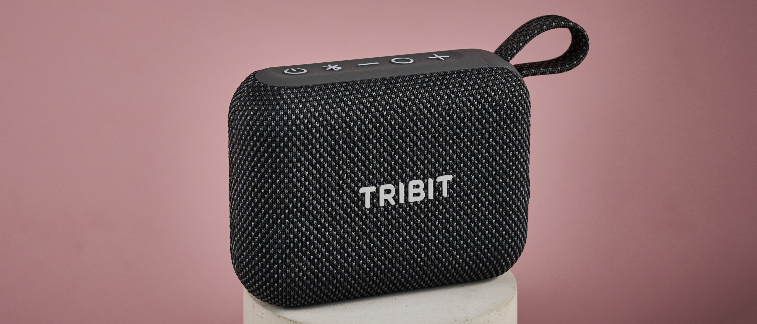 Tribit PocketGo on stand, against pink background