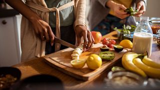 Woman prepping healthy food in the kitchen, with bananas on a chopping board
