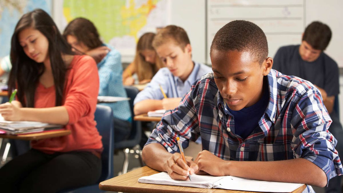 Teenage boy writes in his notebook in a classroom