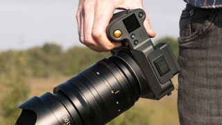 Hasselblad X2D II 100C camera in the hand, outdoors at first light