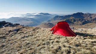 A tent pitched in front of a spectacular mountain view