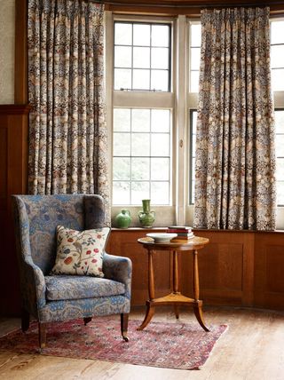 Morris & Co wallpaper and fabrics in a living room with chair in front of window