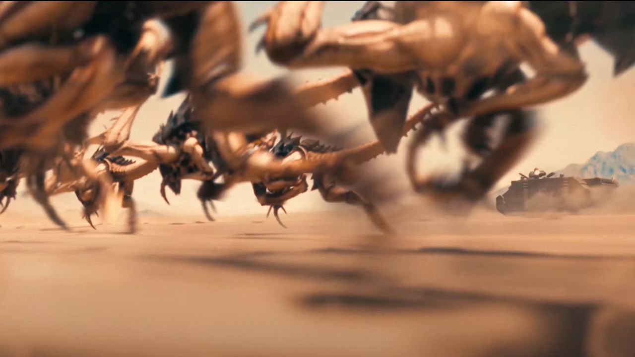 A swarm of alien creatures called Tyranid Hormagaunts running through a desert with a Space Marine Rhino tank in the background.