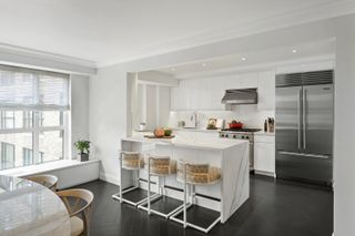 A modern white kitchen with a marble bar and herringbone flooring