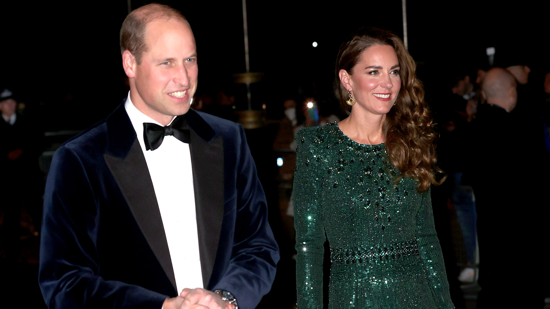 Kate Middleton wearing a green beaded gown walking next to Prince William in a tux