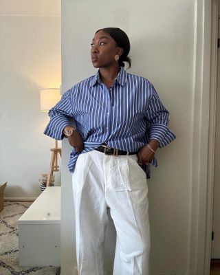 Influencer wearing a blue striped shirt and white trousers.