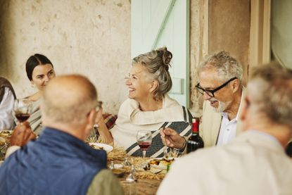 Retirees and younger people dining together at an elegant table. They are either at a senior wedding or have traveled. The location is Morocco.