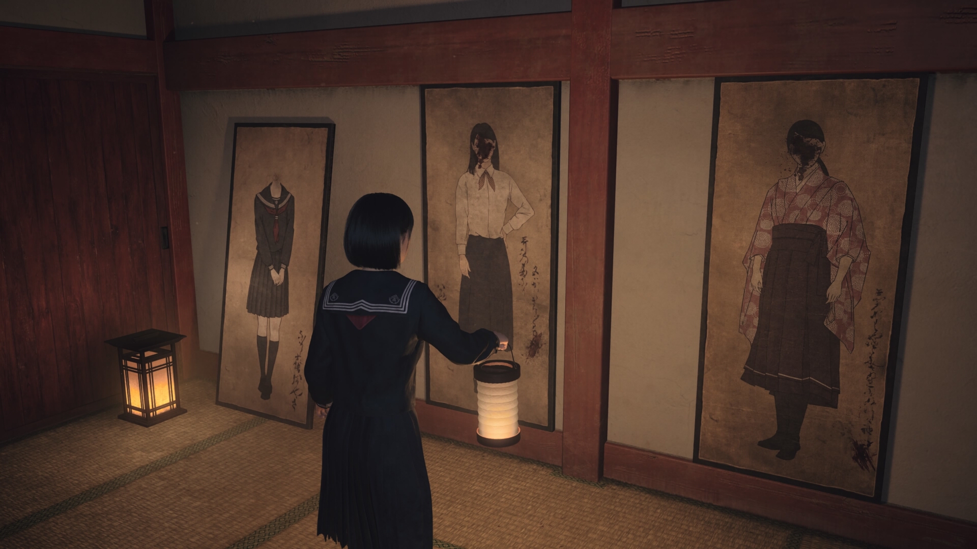 Lantern aloft, Hinako looks at portraits of women hung on a wall in a dark shrine room in Silent Hill f, with their faces obscured by ink splashes