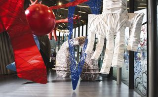 Close up view of Charles Jeffrey's 'The Come Up' exhibition featuring a white 3D hand, red sphere and other colourful sculptures