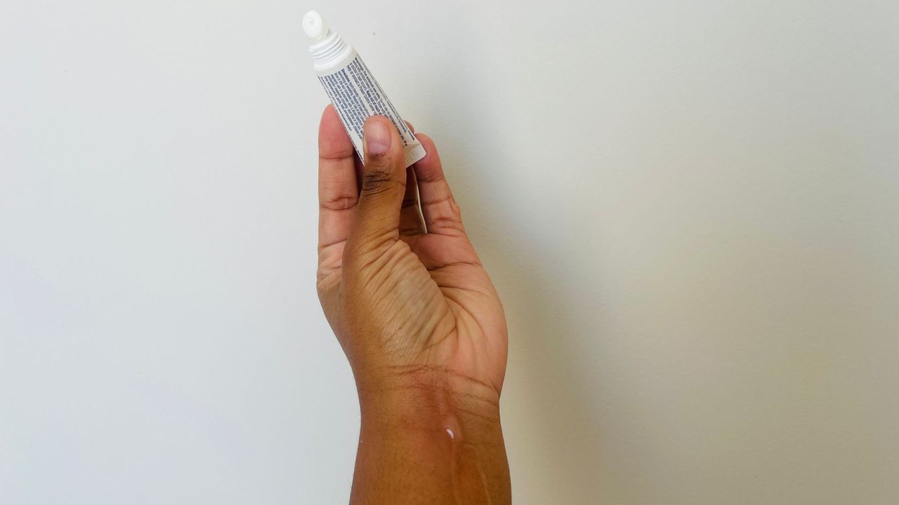 A person holding an opened Aquaphor SPF lip balm.