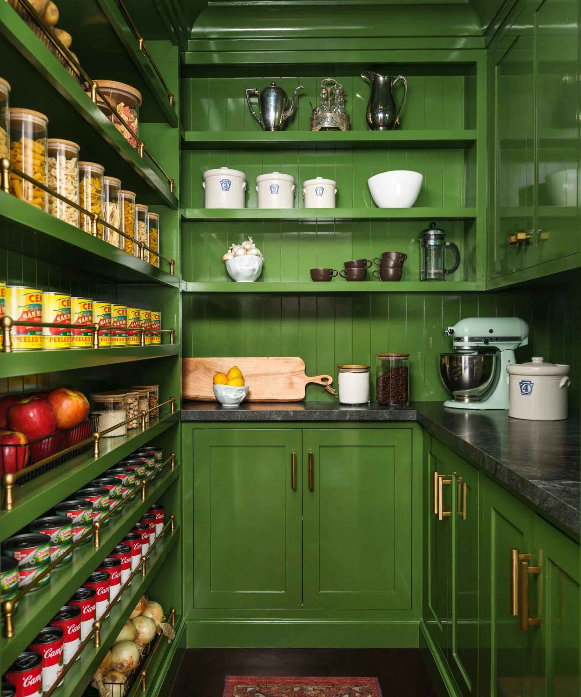 Pantry with green painted shelves and cabinets with china and silverware lined up, tinned food, and kitchen aid mixer