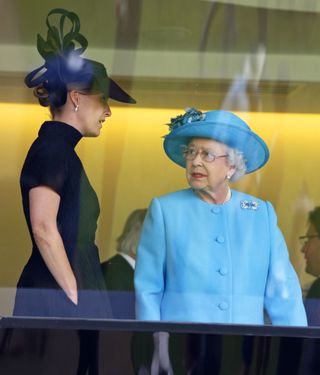 Queen Elizabeth wearing a blue coat and hat talking to Duchess Sophie, wearing a black dress with her hands in her pockets at Royal Ascot 2014