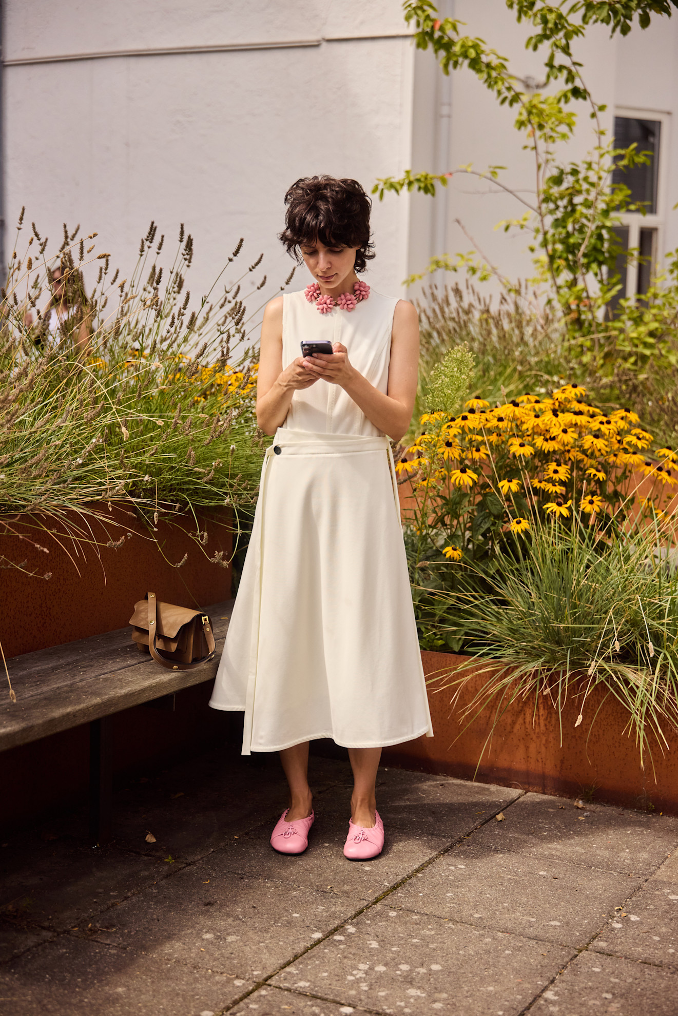 a woman at fashion week wearing a white dress with pink accessories
